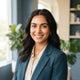 A happy South Asian woman with glowing skin smiling in a bright, professional setting.